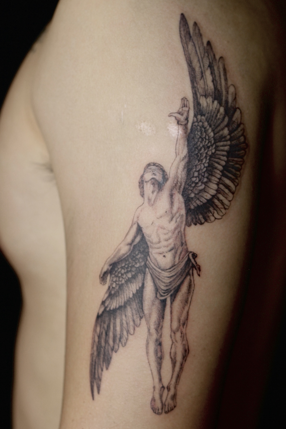Fine-line winged figure tattoo