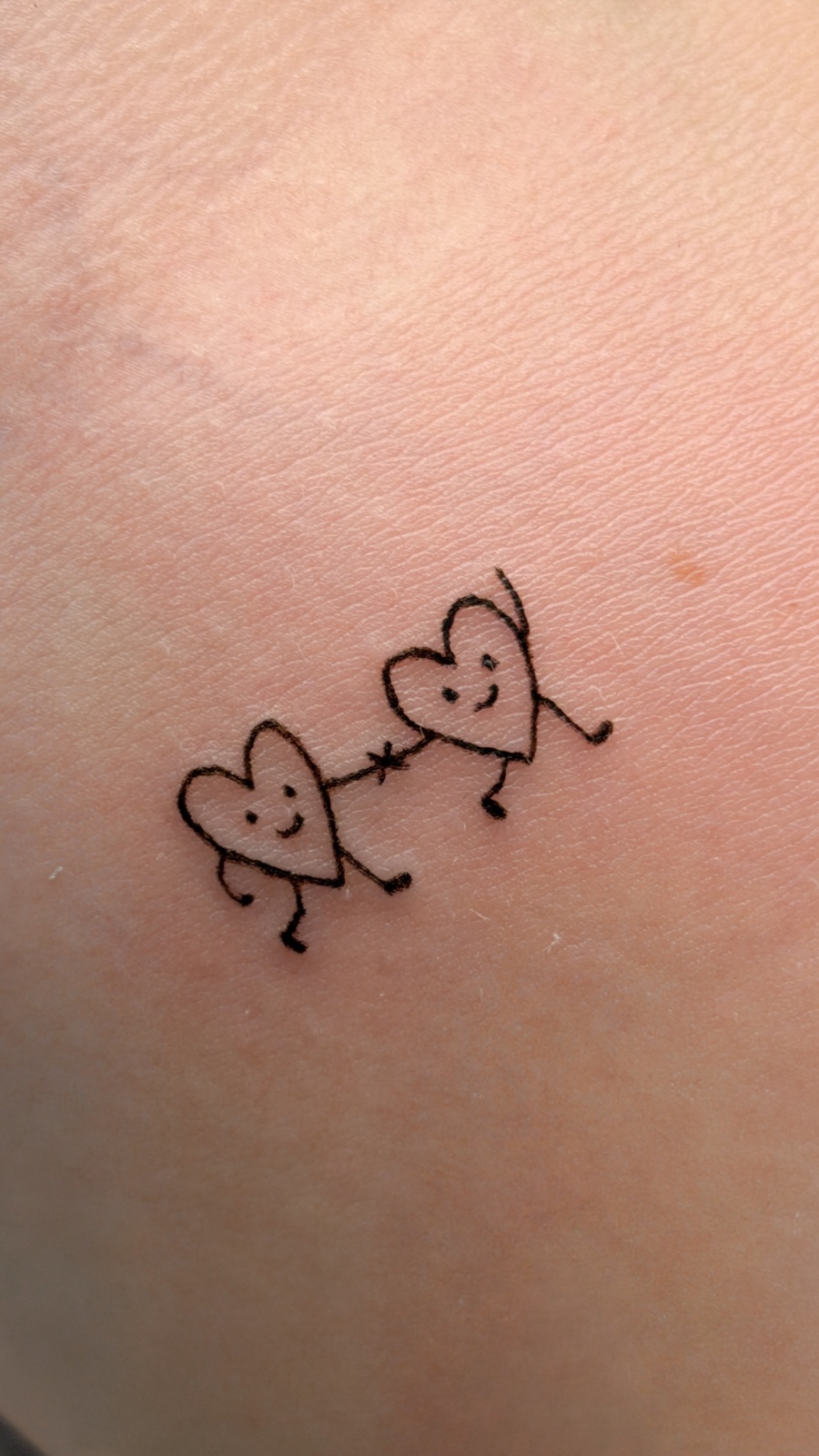 Two tiny connected heart tattoos