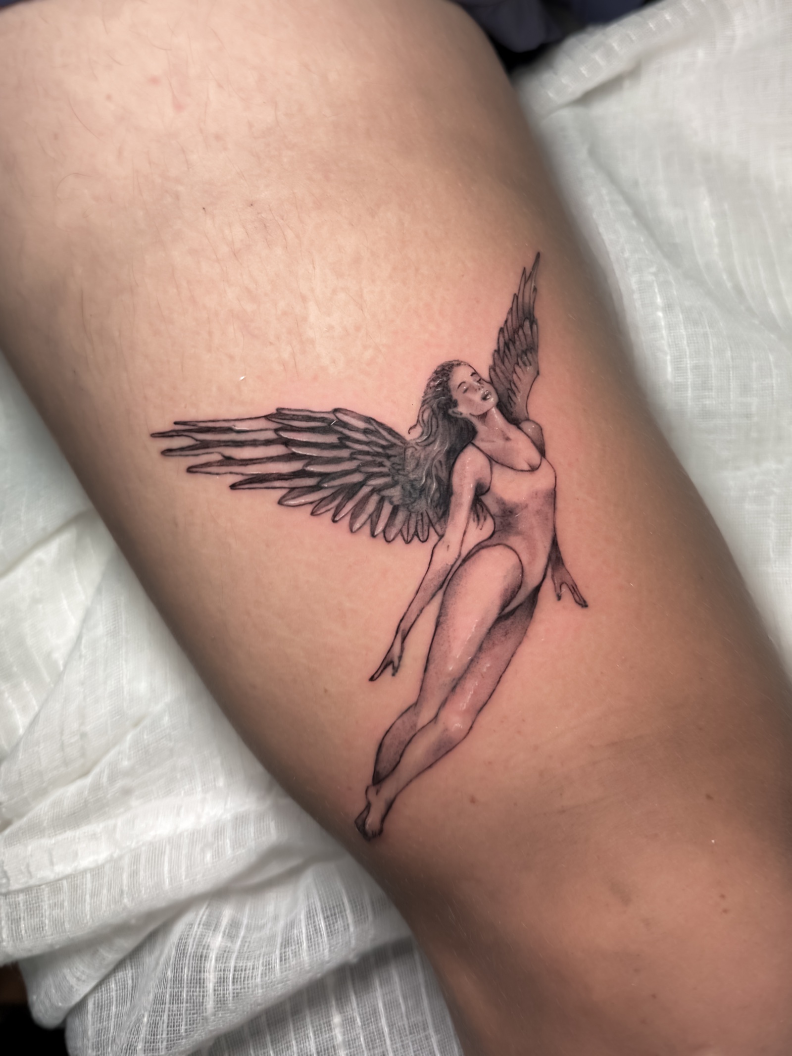 Detailed black-and-grey winged figure tattoo